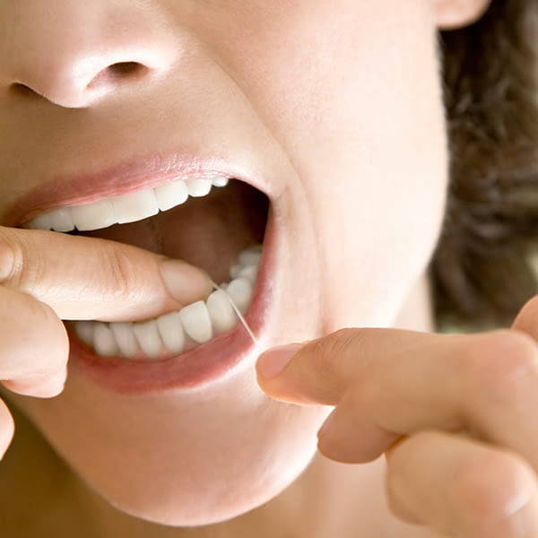 mujer limpia dientes hilo dental