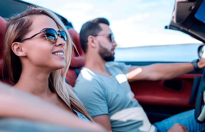 Hombre y mujer conduciendo sonrientes