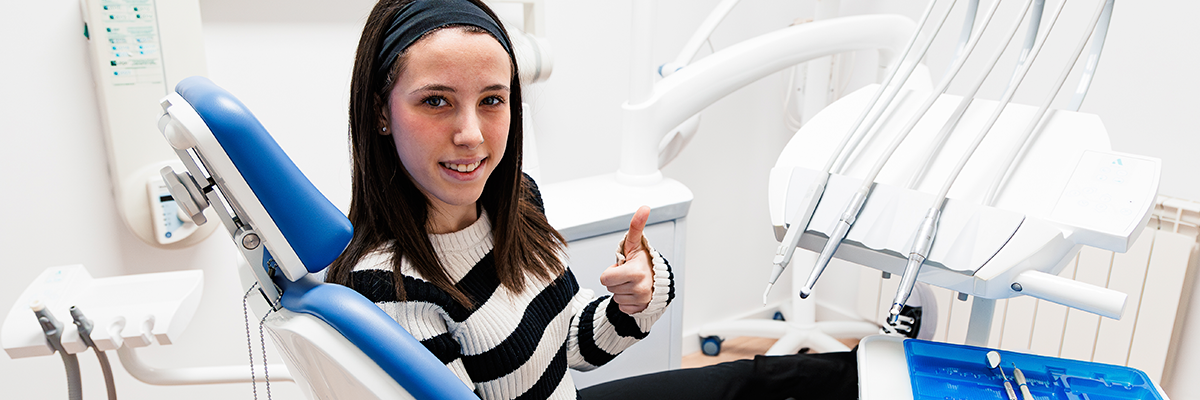 Chica sonriendo en silla dentista